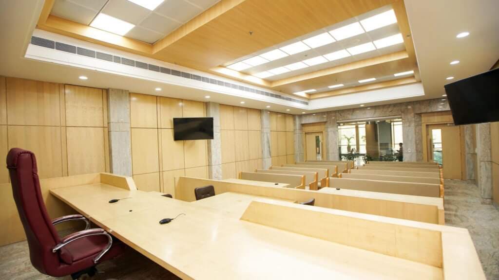 Inside view of a Delhi High Court courtroom with advanced AV technology and modern wooden panelling.